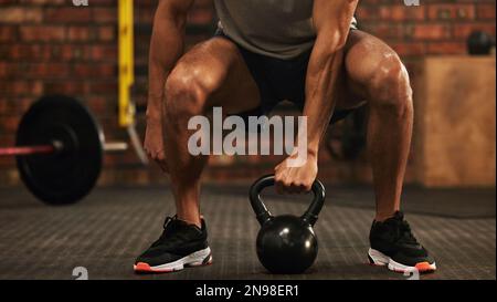 Muscoli fatti dagli dei di idoneità. un uomo irriconoscibile che si allenava con una campana del bollitore in palestra. Foto Stock