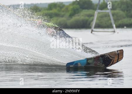 Staffordshire, Regno Unito. Maggio 2018. Wakeboarder surf attraverso il lago utilizzando un cavo di traino Foto Stock