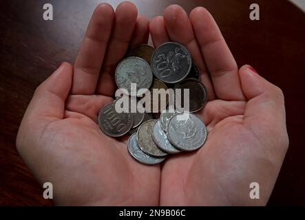 Rupiah monete nel palmo della mano di una donna asiatica Foto Stock