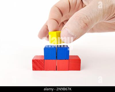 Astratto grafico a piramide multicolore 3D su sfondo bianco, con mano di uomo maturo. Foto Stock