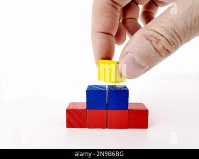 Astratto grafico a piramide multicolore 3D su sfondo bianco, con mano di uomo maturo. Foto Stock