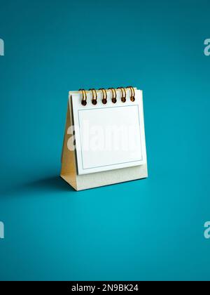 Cornice blu sulla scrivania bianca del calendario per organizzare per pianificare e ricordare la data importante isolato su sfondo blu, verticale, stile minimal Foto Stock