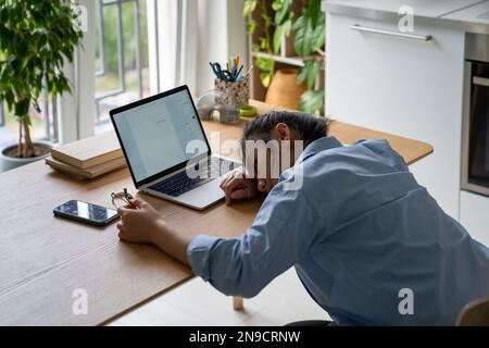 Donna frustrato scrittore freelance sdraiato sulla scrivania con notebook senza motivazione a scrivere Foto Stock