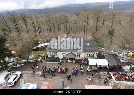 12 febbraio 2023, Sassonia-Anhalt, Stolberg: I visitatori del Winterfest festeggiano sotto il Josephskreuz sull'Auerberg. Dopo una pausa di due anni a causa della pandemia, si tenne nuovamente il festival invernale. Numerosi giochi divertenti, una buona vista dalla piattaforma di osservazione e intrattenimento musicale sono stati offerti ai visitatori. La famosa struttura è una popolare meta escursionistica ed escursionistica e sovrasta la foresta, visibile da lontano, e funge da torre panoramica. Foto: Matthias Bein/dpa/ZB Foto Stock