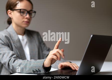 Donna defocusa in background che tocca con il suo dito modello di mockup display virtuale. Foto Stock