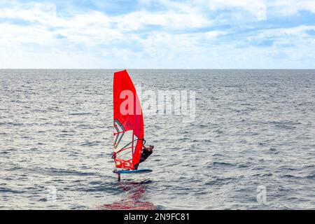 Playa Blanca, Spagna - 29 gennaio 2023: Il windsurf sulla tavola a vela si muove ad una velocità lungo la superficie del mare, sullo sfondo o Foto Stock