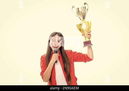 Ragazza adolescente con conversazione microfono della tazza di vincita. Teen in possesso di un trofeo. Il bambino vincitore ha vinto il concorso, celebrando il successo e la vittoria. Foto Stock