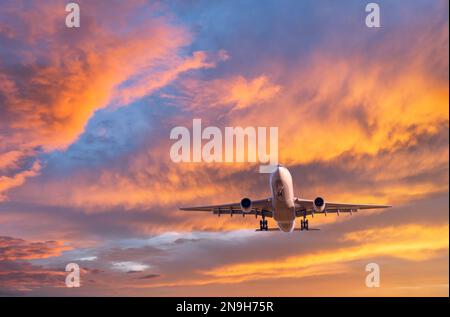 L'aereo vola in cielo colorato al tramonto. Aereo passeggeri Foto Stock