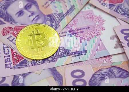 Bitcoin dorato su duecento banconote ucraine hryvnia sfondo. Grivna Ucraina al concetto di Bitcoin Foto Stock