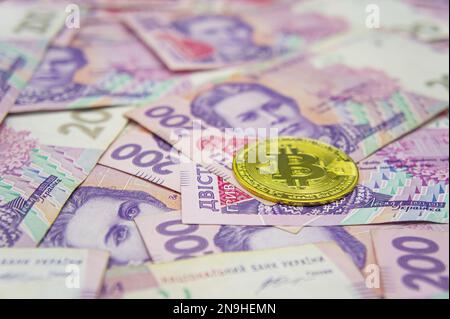 Bitcoin dorato su duecento banconote ucraine hryvnia sfondo. Grivna Ucraina al concetto di Bitcoin Foto Stock
