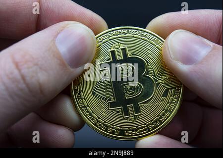 Concetto di trasferimento Bitcoin da mano a mano. Foto di alta qualità. Tenere il dito bitcoin dorato su nero isolato. Portamonete oro bitcoin cripto digitale mo Foto Stock