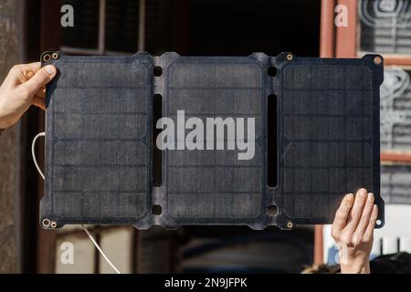 Batteria solare portatile in mano maschio e femmina. Ricarica di gadget mobili in natura senza elettricità. Concetto di fonte di energia alternativa. Foto Stock