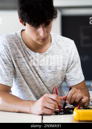 Giovane studente maschio che impara la programmazione elettronica in laboratorio Foto Stock