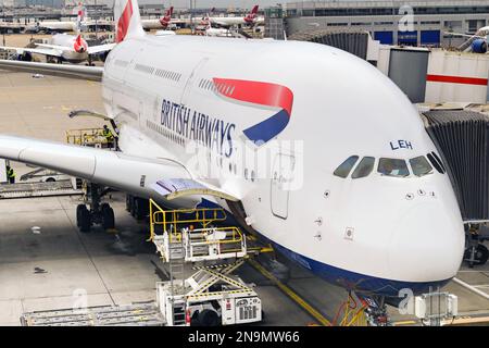 Londra, Regno Unito - febbraio 2023: British Airways Airbus A380 JET (immatricolazione G-XLEH) presso un terminal aeroportuale con un veicolo per il carico di pallet Foto Stock