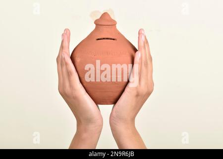 Banca indiana di maialino o gullak in mano su sfondo bianco Foto Stock