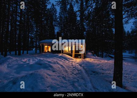 Accogliente cabina in legno in una foresta innevata nel nord della Svezia, Kiruna Foto Stock