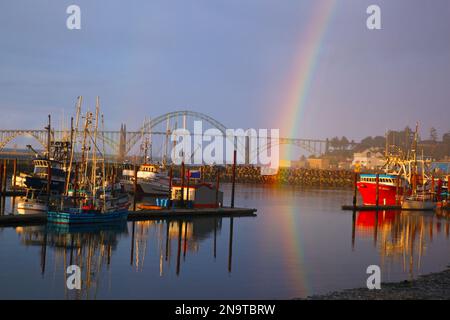 Arcobaleno al mattino sopra il ponte della baia di Yaquina e le barche da pesca nel porto; Newport, Oregon, Stati Uniti d'America Foto Stock