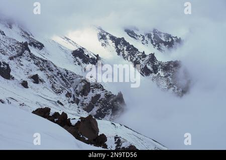 Crinale di montagna innevato e nuvole in Sicilia, pendio della Valle del Bove nel Parco Nazionale dell'Etna Foto Stock