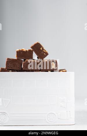 Pezzi di cioccolato fondente in una lattina di metallo bianco, cioccolato fondente di arachidi fatto in casa impilati in una lattina di metallo Foto Stock