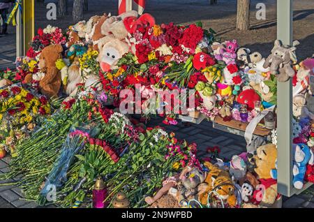 Fiori di dolore, giocattoli e lampade icone su panchina vicino edificio residenziale distrutto dal missile russo il 14 gennaio 2023 nella residenziale Pobeda A. Foto Stock