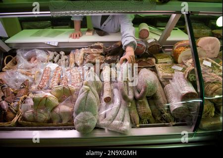 La donna organizza la merce in un negozio di carne a Locana, Italia; Locana, Italia Foto Stock