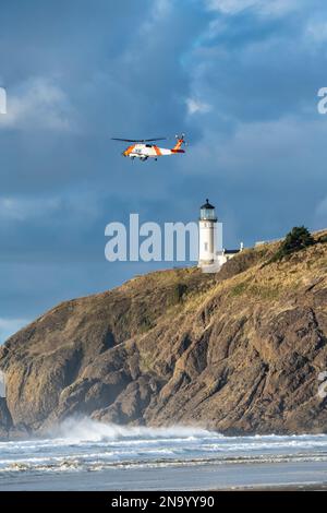 Elicottero della US Coast Guard che vola vicino al faro North Head di Cape Disappointment durante una missione di addestramento Foto Stock