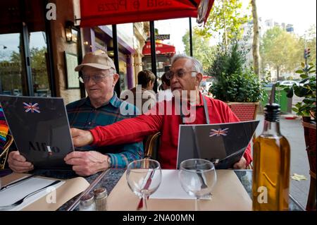 Due uomini guardano i menu in un ristorante di Parigi, Francia; Parigi, Francia Foto Stock