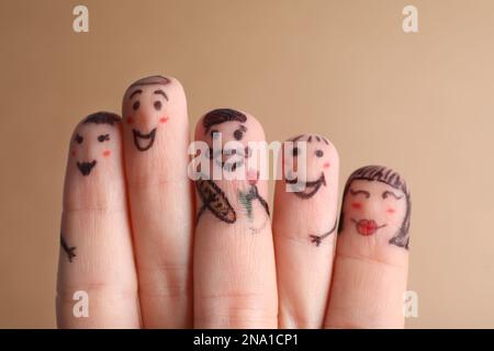 Cinque dita con disegni di volti felici su sfondo marrone Foto Stock