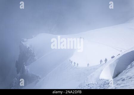 Gli alpinisti si dirigono verso il Monte bianco nella nebbia, visti da Aiguille du Midi; Chamonix-Mont-Blanc, alta Savoia, Francia Foto Stock