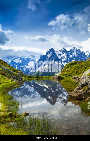 Aiguille des Charmoz, parte di Aiguilles de Chamonix, si riflette sul Lac Flegere circondato da prato verde, Aiguilles Rouges Foto Stock