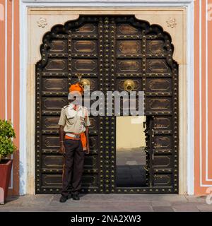 Uomo in piedi fuori di una porta ornata al Palazzo della Città; Jaipur, Rajasthan, India Foto Stock
