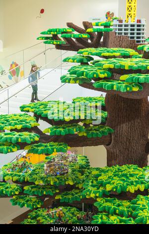 Ragazza che guarda su un gigantesco albero di Lego nella Lego House; Billund, Danimarca Foto Stock