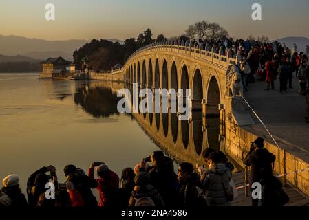 Folla di turisti che fotografano il Ponte dell'Arco del 17 al tramonto, il Palazzo d'Estate, Pechino, Cina © Dosfotos/Axiom Foto Stock