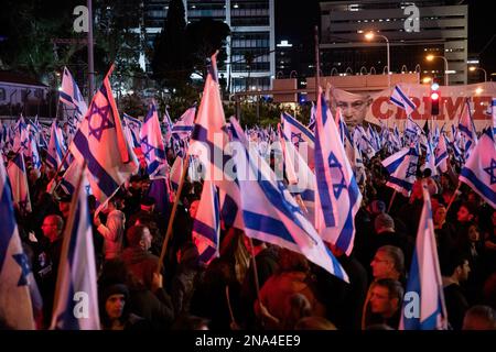 Tel Aviv, Israele. 11th Feb, 2023. I manifestanti detengono bandiere israeliane durante la manifestazione. Più di 130.000 persone hanno protestato a Tel Aviv contro il governo di estrema destra di Netanyahu ed è una controversa riforma legale. Credit: SOPA Images Limited/Alamy Live News Foto Stock