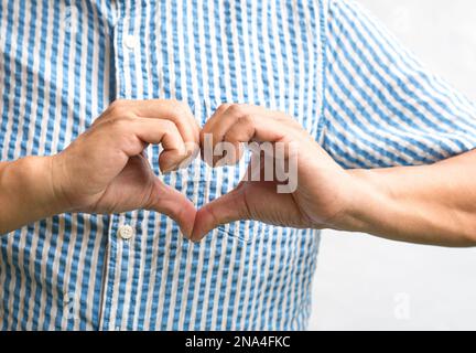 Uomo che mostra la forma del cuore fatto con le mani. Primo piano. Foto Stock