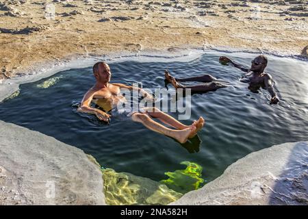 Uomini che fanno il bagno in una piscina di salamoia nelle saline del lago Karum (lago Assale), depressione Danakil; regione di Afar, Etiopia Foto Stock