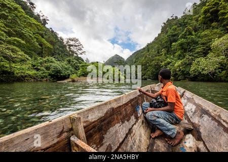 Ragazzo Papuano su una barca sul fiume Warsambin; Papua Occidentale, Indonesia Foto Stock