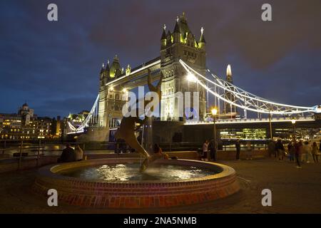 Tower Bridge sul Tamigi e The Shard illuminato al crepuscolo con una fontana e turisti in primo piano; Londra, Inghilterra Foto Stock