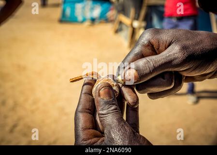 Le mani dell'uomo creano intricatamente un oggetto da vendere al mercato dell'artigianato degli intagliatori di legno di Okahandja Mbangura; Okahandja, regione di Otjozondjupa, Namibia Foto Stock