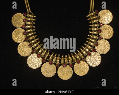 una collana d'oro vintage con un design ornato e sculture dettagliate che è stato utilizzato dai re esposti su uno sfondo nero Foto Stock