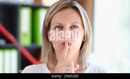 Donna adulta tiene il dito sulle labbra e gesti per essere silenziosa e mantenere segreto. Foto Stock