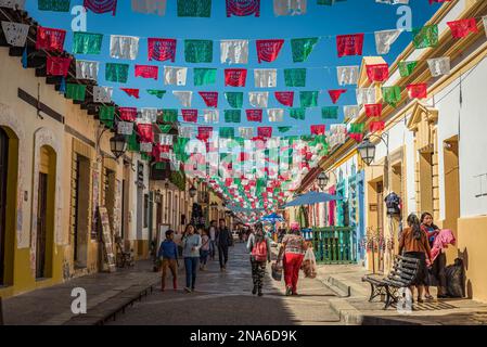 Le ghirlande si estendevano lungo una strada tra edifici e pedoni a piedi; San Cristobal de las Casas, Chiapas, Messico Foto Stock