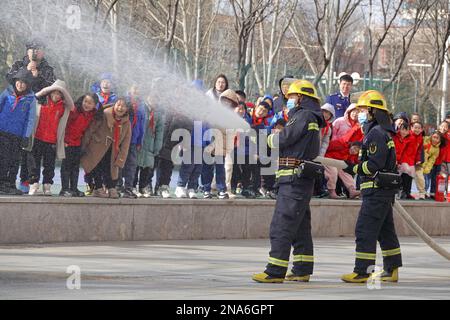 YANTAI, CINA - 13 FEBBRAIO 2023 - i vigili del fuoco mostrano abilità antincendio agli studenti della scuola elementare sperimentale di Laishan a Yantai, Chin orientale Foto Stock