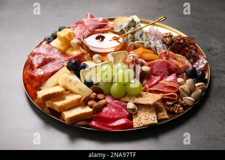 Piatto di antipasti diversi con miele su tavolo grigio, primo piano Foto Stock