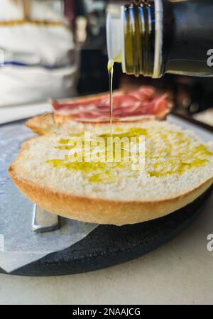 Versare l'olio d'oliva sulla fetta di pane tostato appena fatta. Messa a fuoco selettiva Foto Stock