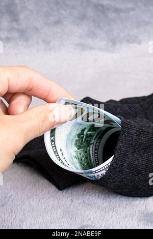 Dollari in calzino e mano su uno sfondo grigio Foto Stock