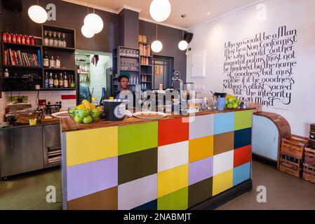 Lavoratore dietro un bancone colorato in un ristorante; città del Capo, Sudafrica Foto Stock