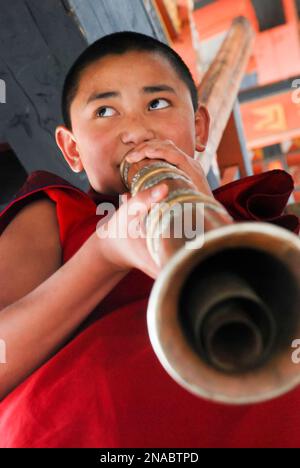 Nel Punakha Dzong di Punakha, Bhutan, un giovane monaco suona un lingm, uno strumento musicale tradizionale in Bhutan; Punakha, Bhutan Foto Stock