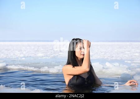 Donna che si immerge in acqua ghiacciata il giorno d'inverno. Battesimo rituale Foto Stock