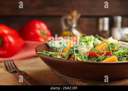 Deliziosa insalata di verdure con microgreens servita su tavolo di legno, primo piano Foto Stock